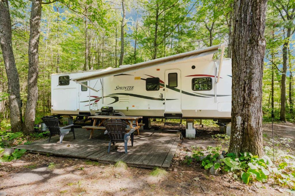 ein Wohnmobil im Wald mit einem Tisch und Stühlen in der Unterkunft 2-bedroom Camper Trailer Cottage #3 in Dillon