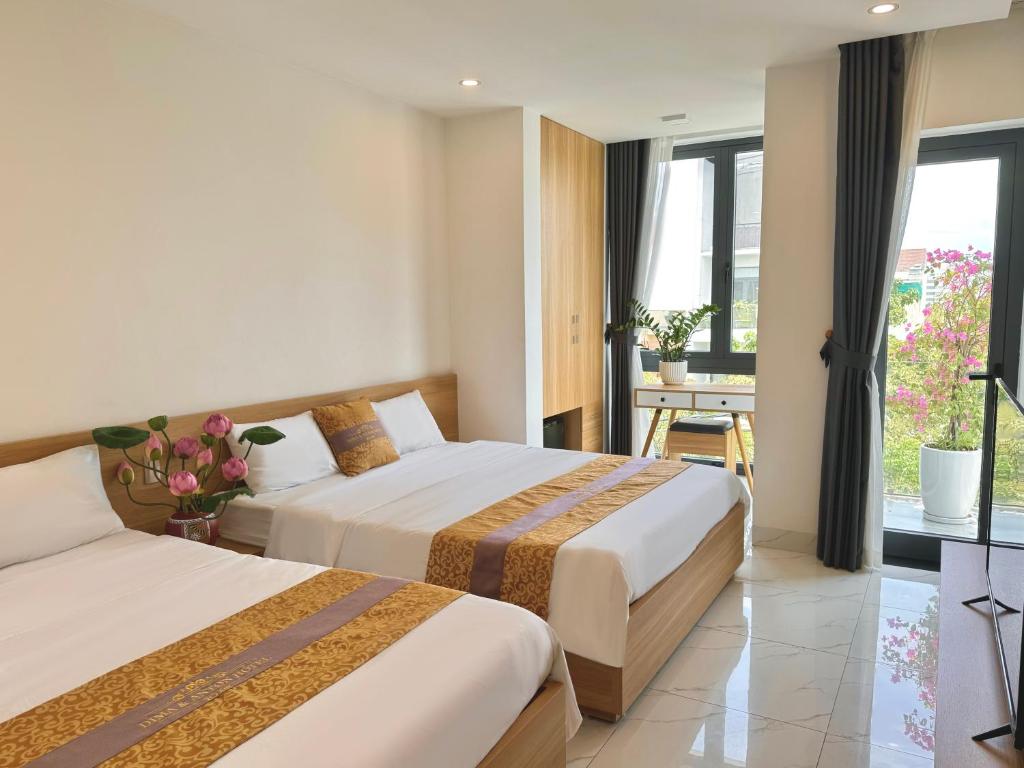 une chambre d'hôtel avec deux lits et un balcon dans l'établissement D & A Homestay Hue, à Hue