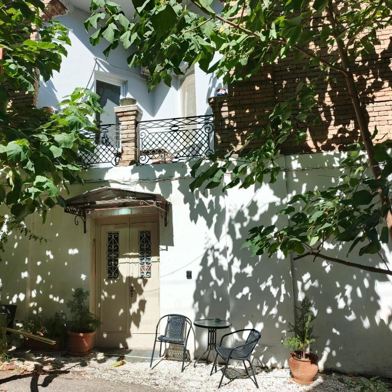 第比利斯Ambience Hostel & Apartments的白色的房子,配有椅子和桌子