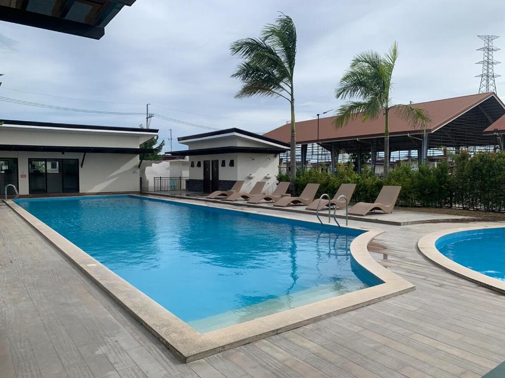a swimming pool with lounge chairs next to a building at Ellie's Tiny House - Cozy Getaway with Kitchen & Pool Access near SM Dasmariñas in Dasmariñas