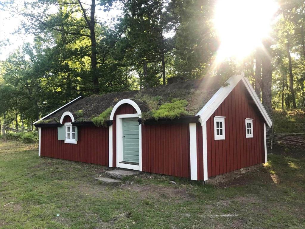 a red shed with a grass roof with the sun behind it at KRO073-Tingsryd-Groenvik-5 in Siggamåla