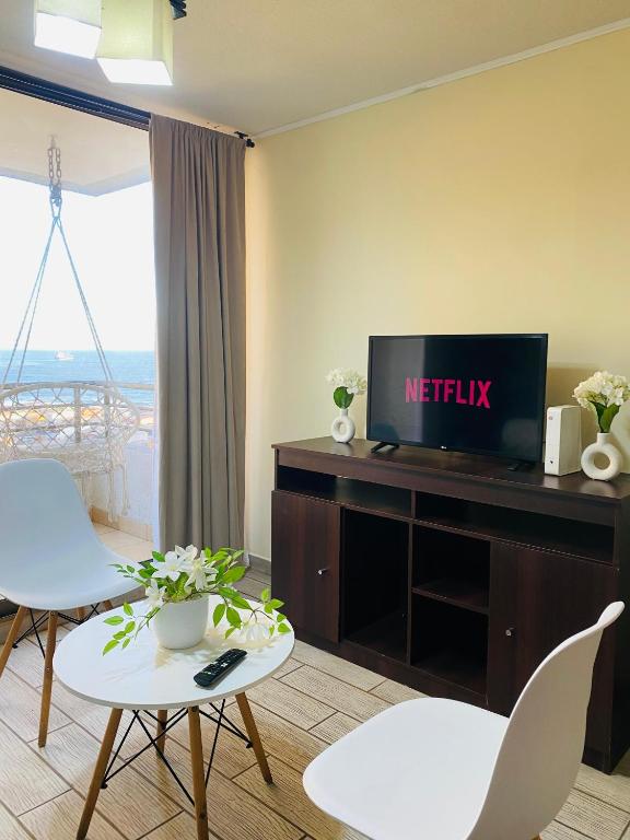 a living room with a television and white chairs at Experiencia 2Terramar 1Hab-1Baño-1 Estac in Antofagasta