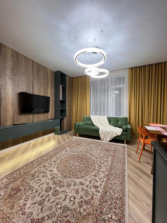 a living room with a green couch and a television at Апартаменты в центре Астаны in Astana