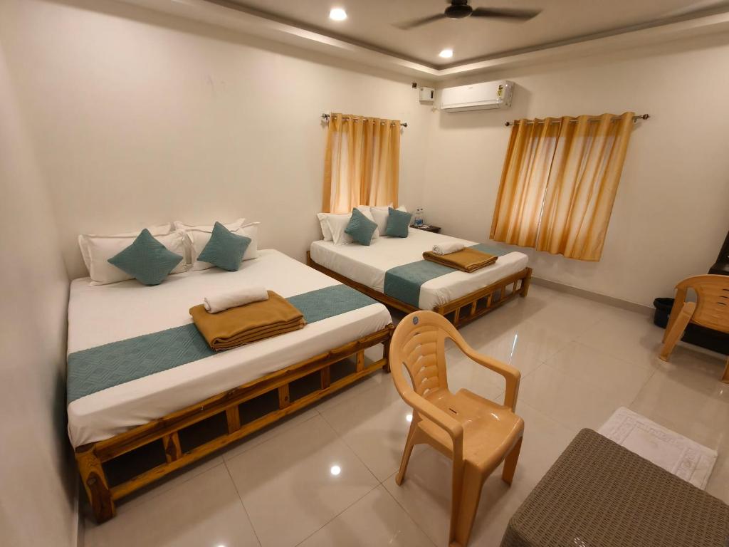 - 2 lits dans une chambre avec une chaise et une table dans l'établissement Saai Residency Tiruvannamalai, à Tiruvannāmalai