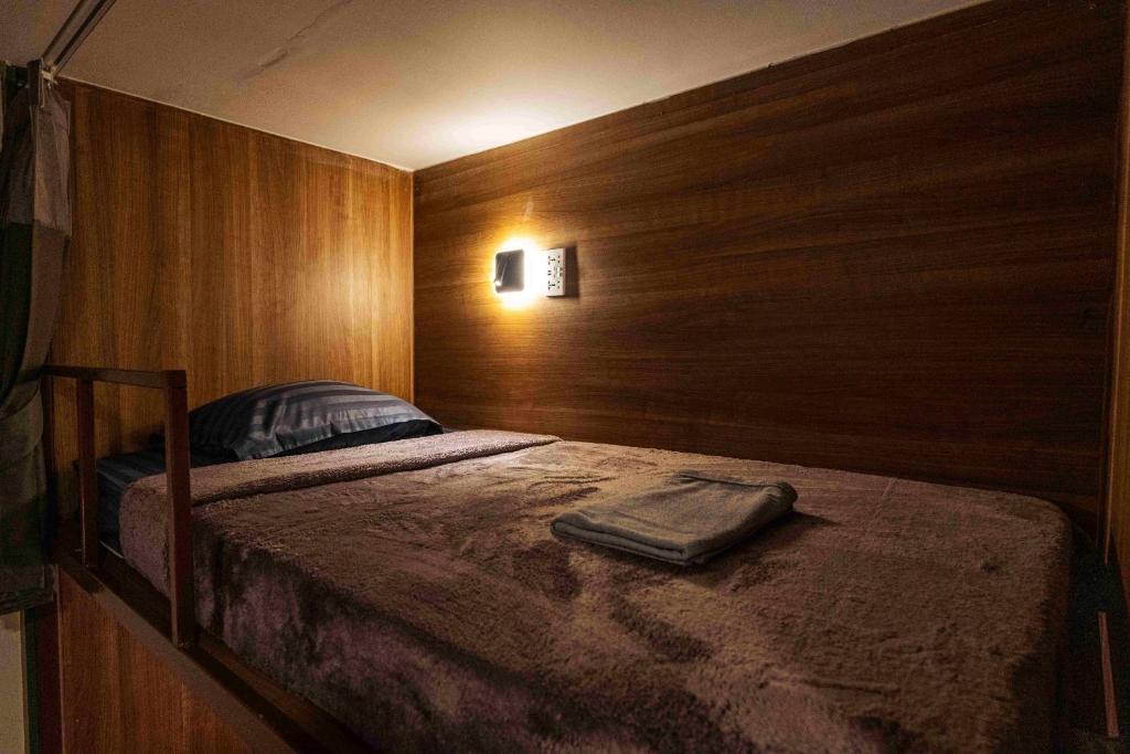 a bedroom with a bed with a wooden wall at hotel Rue de Saim in Bang Rak