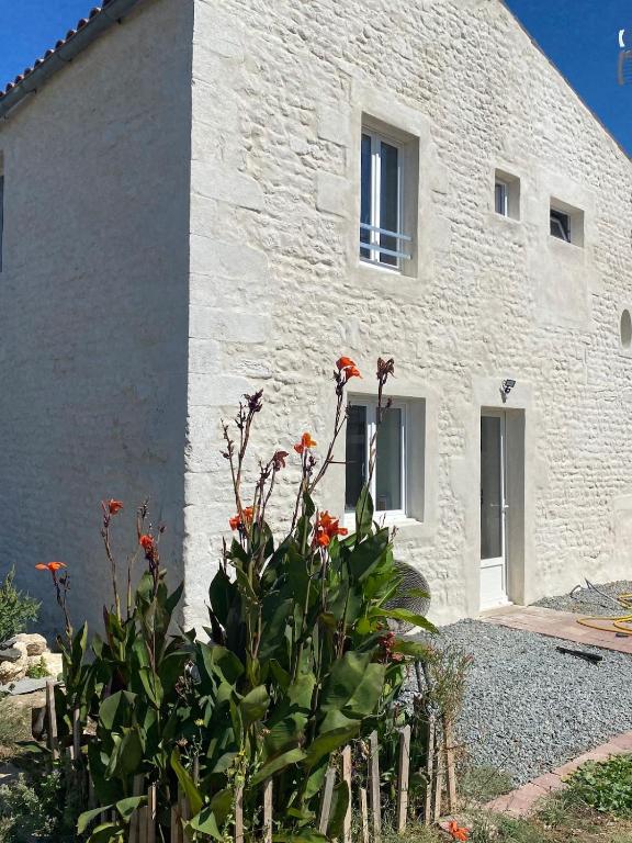 a white building with flowers in front of it at La plage et le calme in Marennes