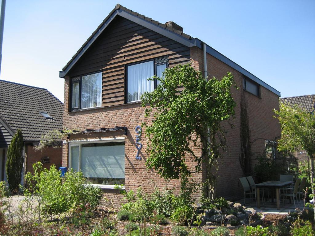 una casa de ladrillo con un árbol delante de ella en Bed and Breakfast De Mozaiektegel Uden, en Uden