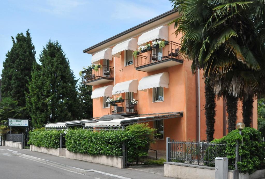 un grande edificio arancione con balconi e piante di Albergo Valentina a Peschiera del Garda