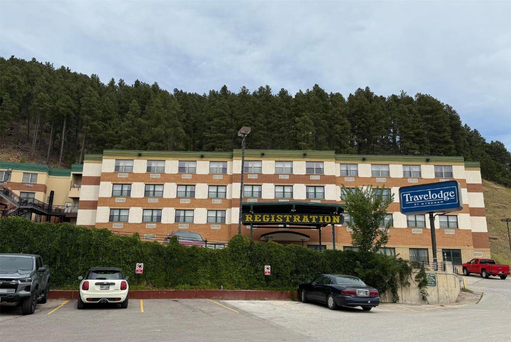 a large building with cars parked in a parking lot at Travelodge by Wyndham Deadwood in Deadwood
