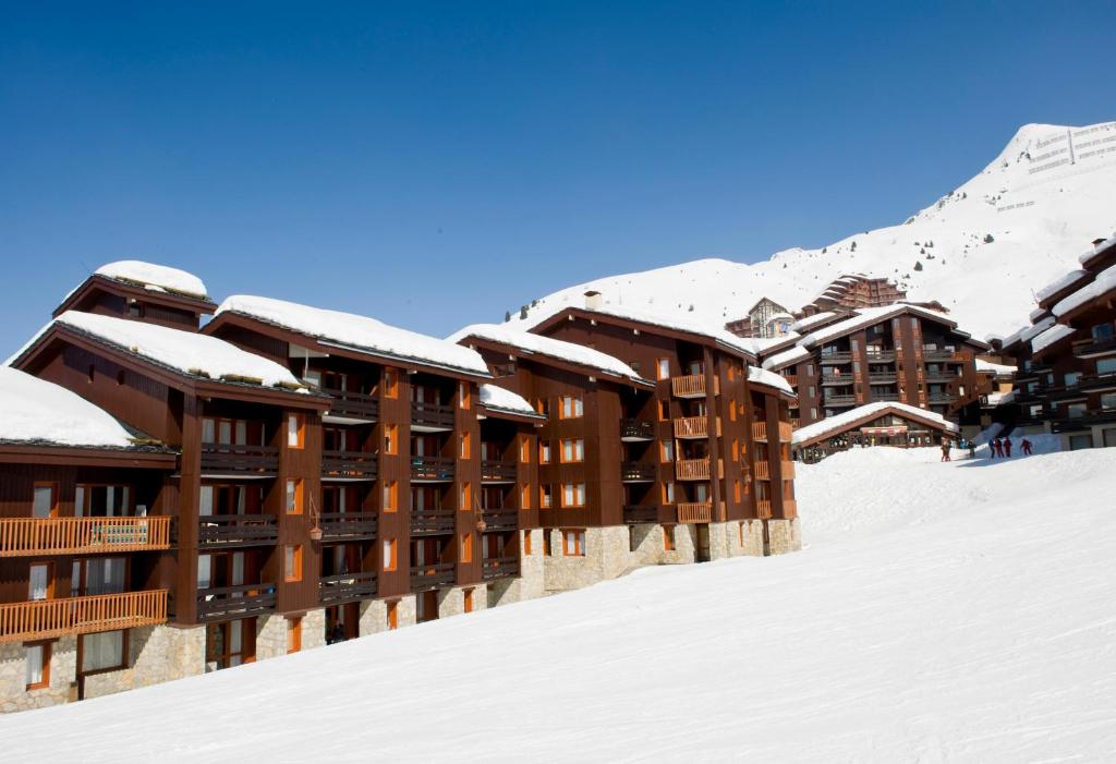 a hotel in the snow with snow covered buildings at Residence Les Chalets des Arolles - maeva Home in Mâcot La Plagne