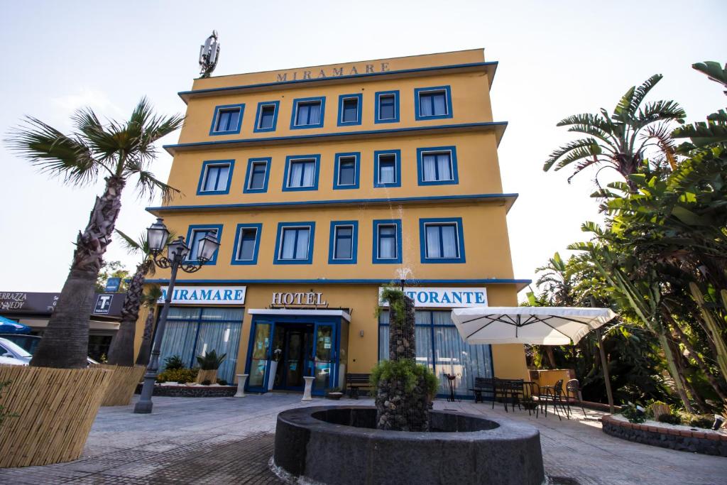 een geel gebouw met een paraplu ervoor bij Miramare Hotel in Catania