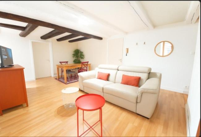 a living room with a white couch and a red stool at Les remparts in Ensisheim