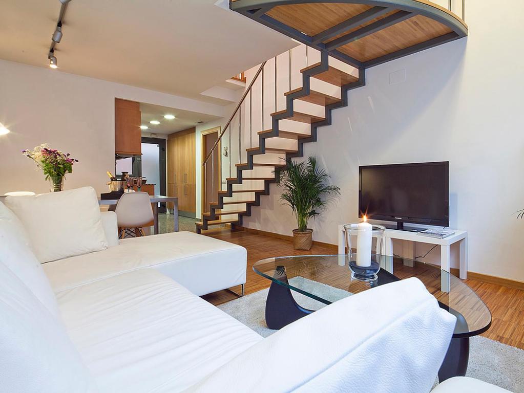una sala de estar con muebles blancos y una escalera. en Apartment Barcelona Rentals - Park Güell Apartments, en Barcelona
