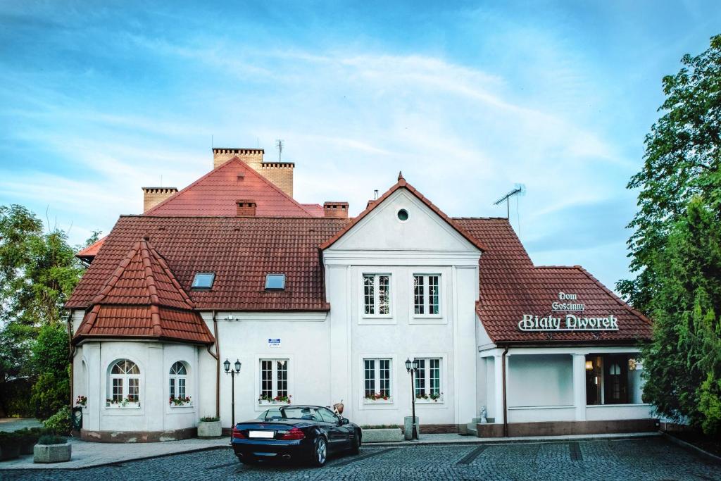 a car parked in front of a white building at Dom Goscinny Bialy Dworek in Człuchów