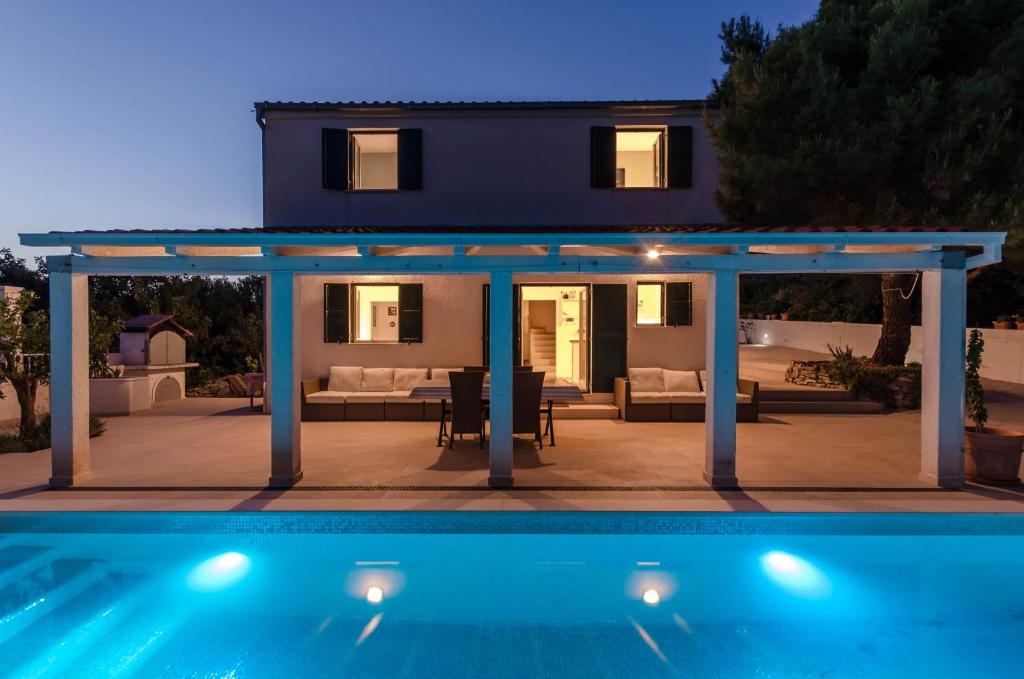 a villa with a swimming pool in front of a house at Holiday home Voga in Maslinica