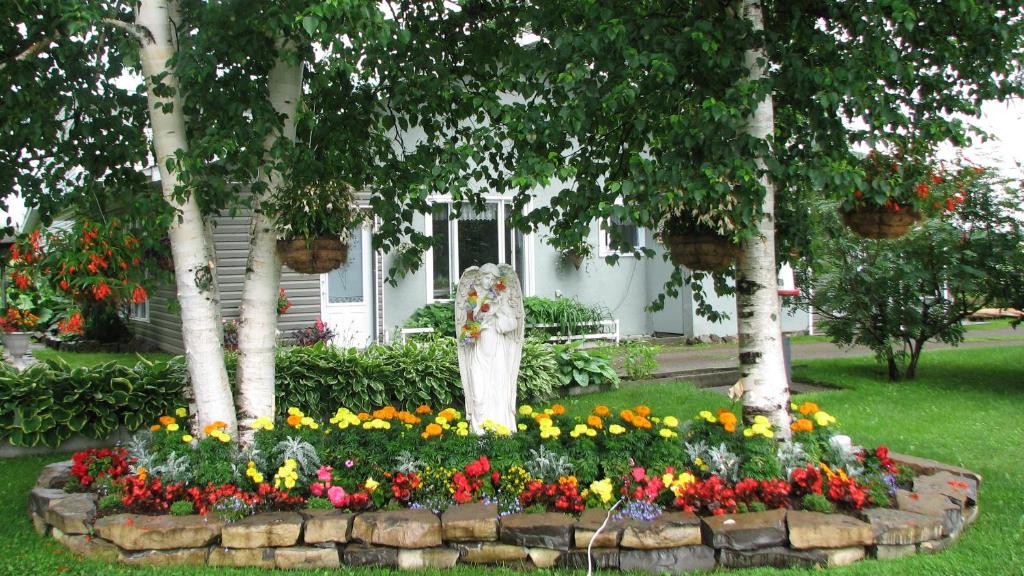 a statue in a flower garden in front of a house at Appartement de l'Ange in Saint-Honoré