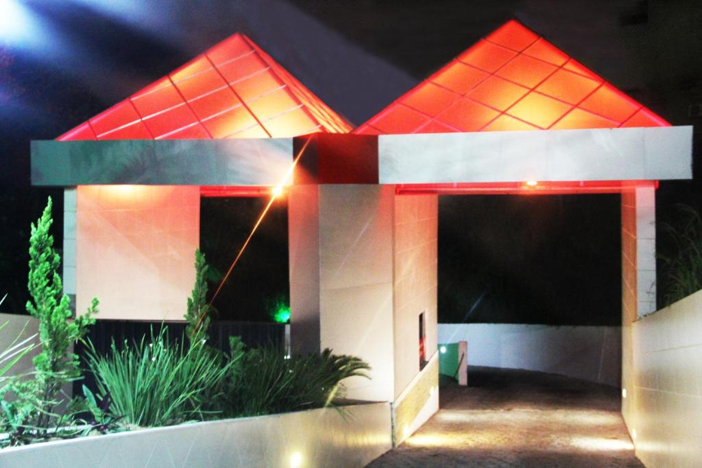 una pequeña casa con techo rojo por la noche en DOM Suites motel (Adult Only) en Salvador