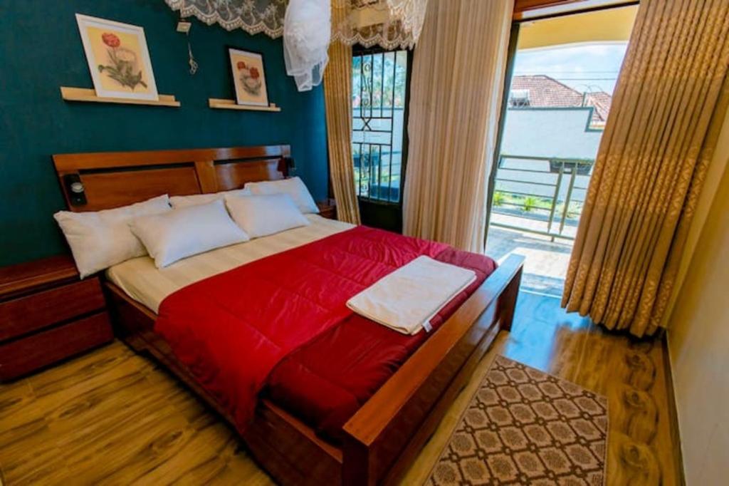een slaapkamer met een bed met rode lakens en een raam bij Homescapes in Kigali