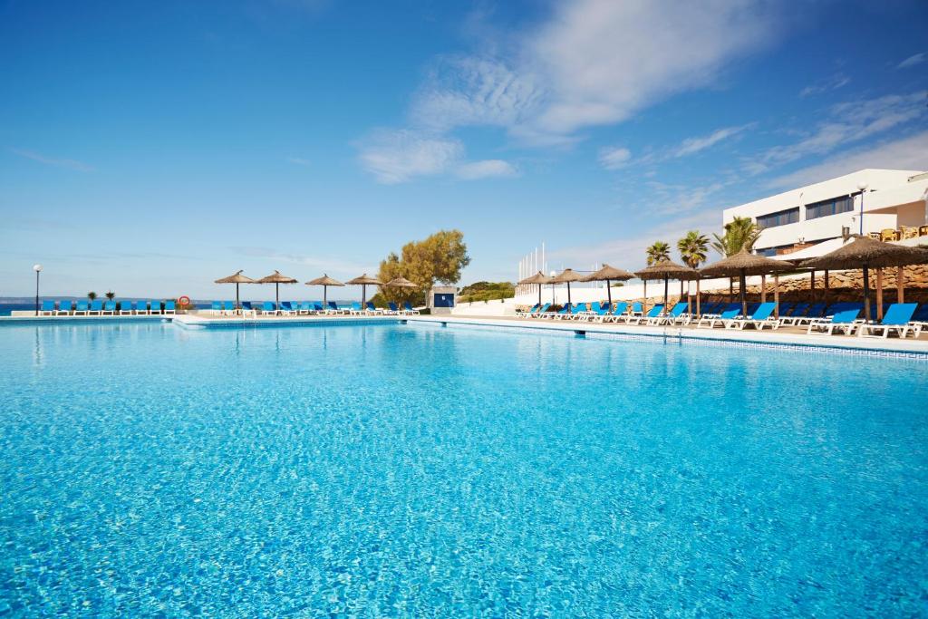 a large swimming pool with blue water and umbrellas at Insotel Club Maryland in Playa Migjorn