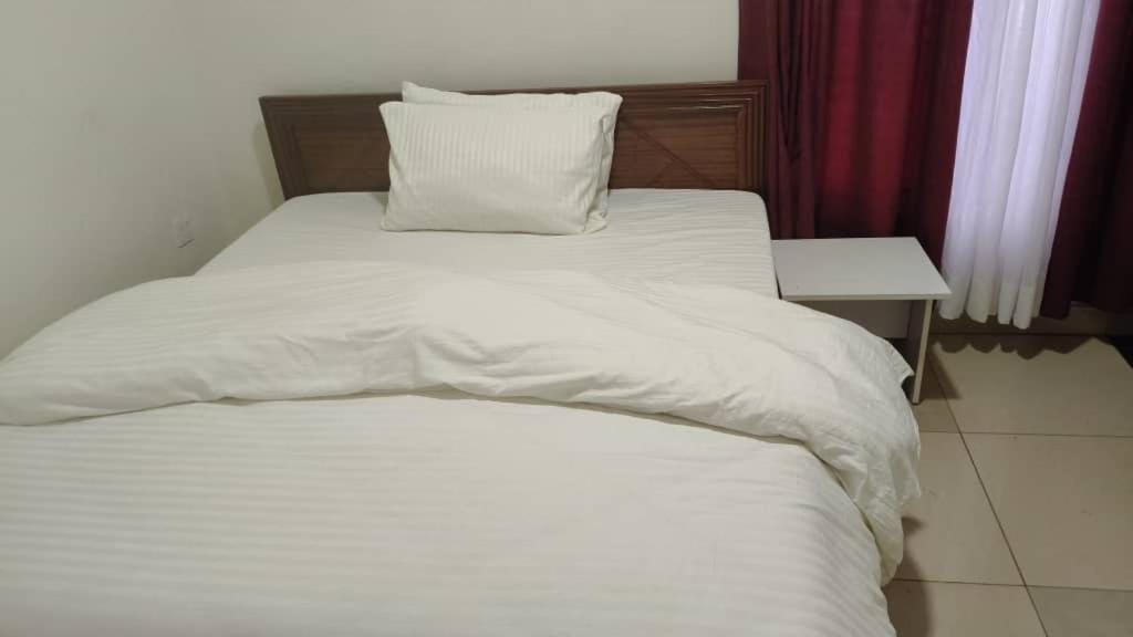 a bed with white sheets and a pillow on it at Apartment in Kigali