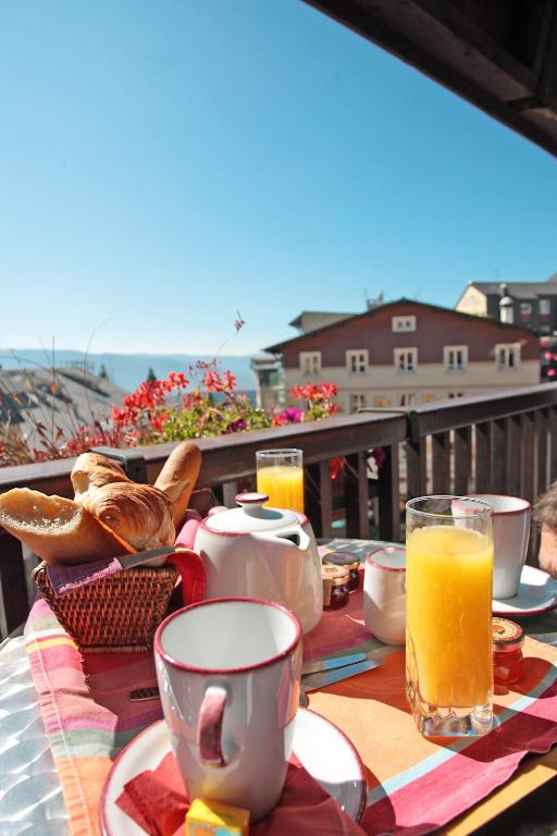 a table with food and orange juice on a balcony at Le Grand Tétras in Font-Romeu