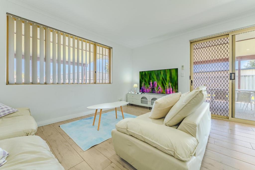 a living room with a white couch and a tv at Bright Airy Retreat with Garden in Waikiki
