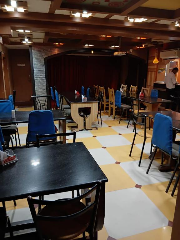 a dining room with tables and chairs and a stage at Hotel Thalapathi in Chennai