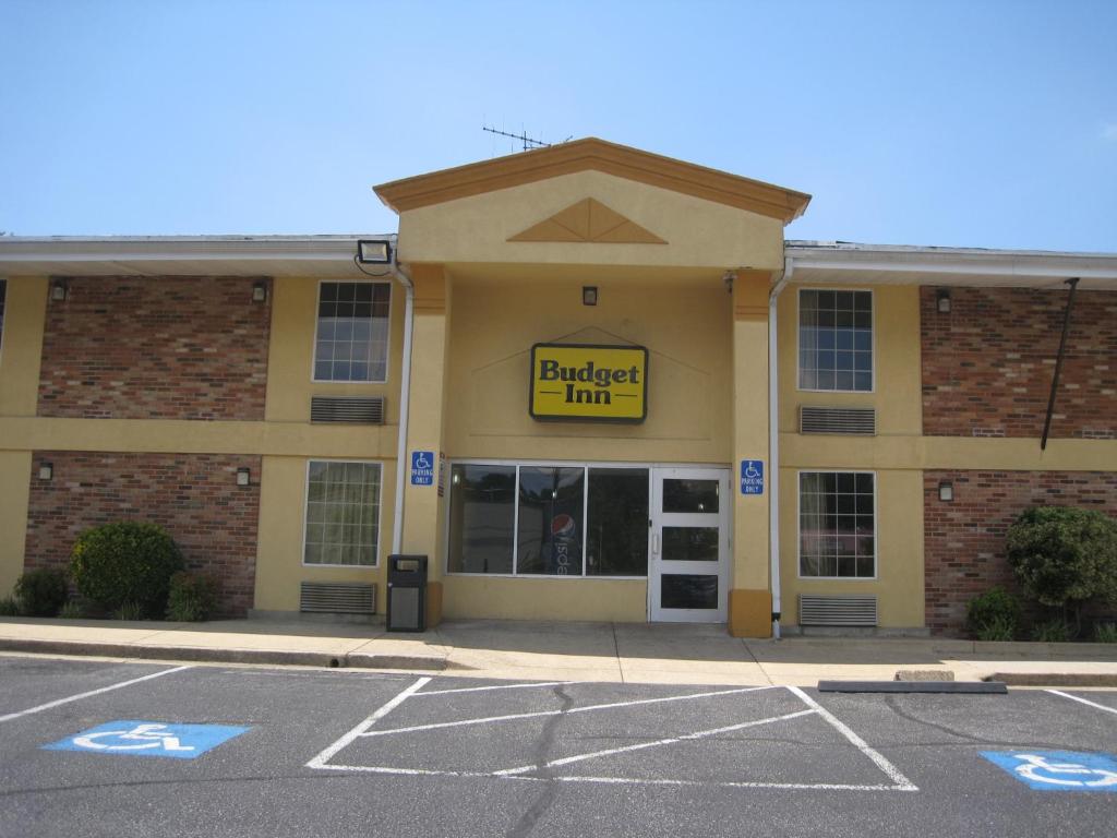 um edifício com uma placa de pousada de bico amarelo num parque de estacionamento em Budget Inn Temple Hills em Temple Hills