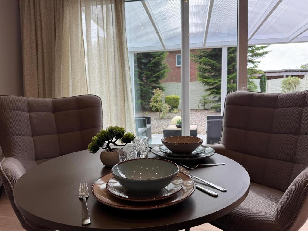 uma mesa de jantar com duas cadeiras e uma mesa com pratos em Küstenzeit Apartment Varel em Varel