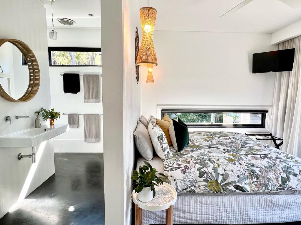 a bedroom in a tiny house with a bed and a sink at Quenda Guesthouse in Hovea