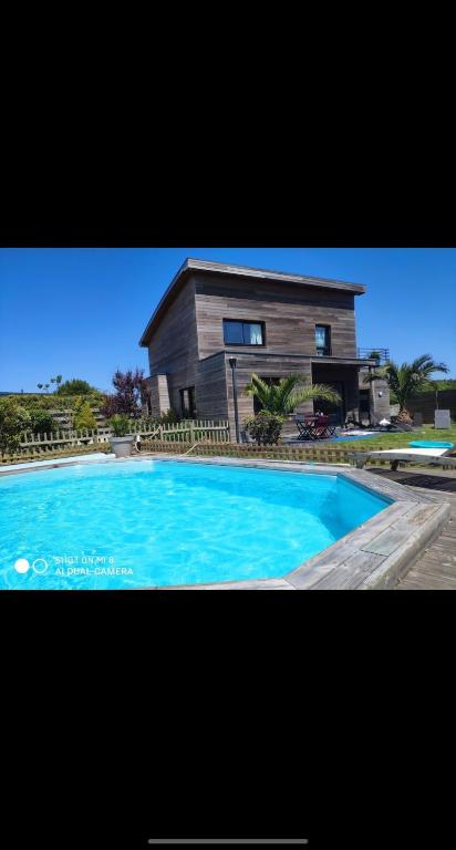 a large blue swimming pool in front of a house at Belle Maison bois avec piscine proche de la plage in Landéda