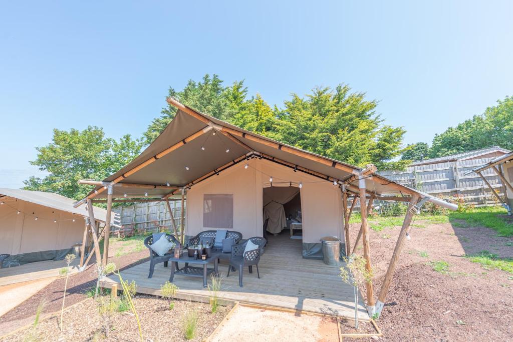 ein Zelt mit einem Tisch und Stühlen auf einem Deck in der Unterkunft Stags head Safari Tents in Abbotskerswell