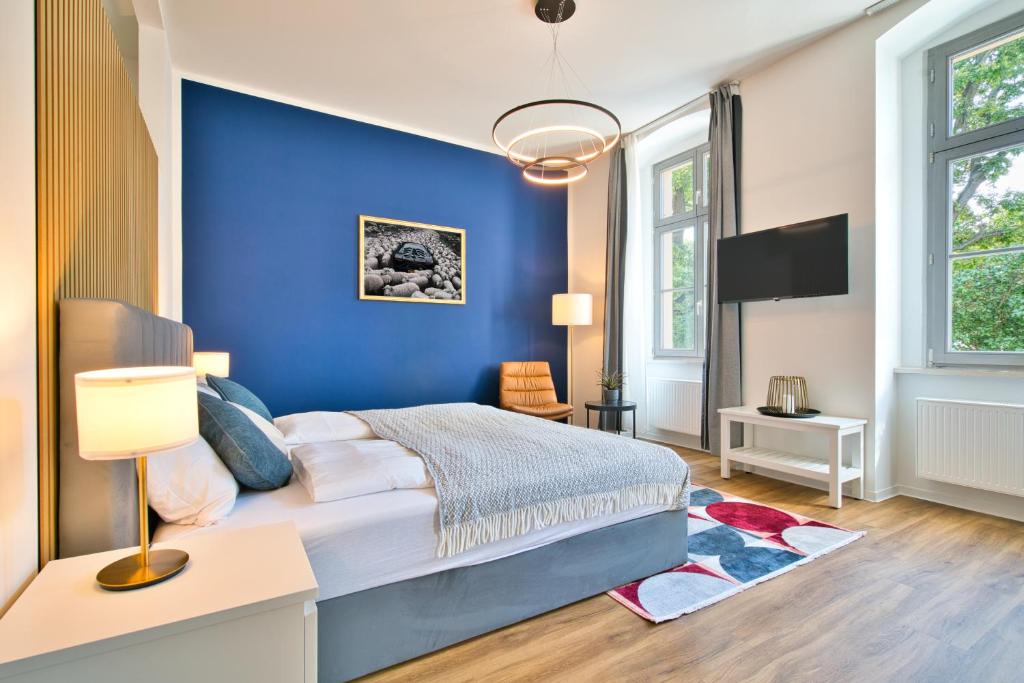 - une chambre bleue avec un lit et une télévision dans l'établissement Halle Suites by FullHouse - free parking & WiFi, à Halle-sur-Saale
