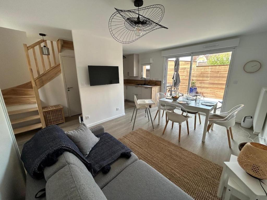 a living room with a couch and a dining room at Maison neuve proche plage et commerces in Stella-Plage