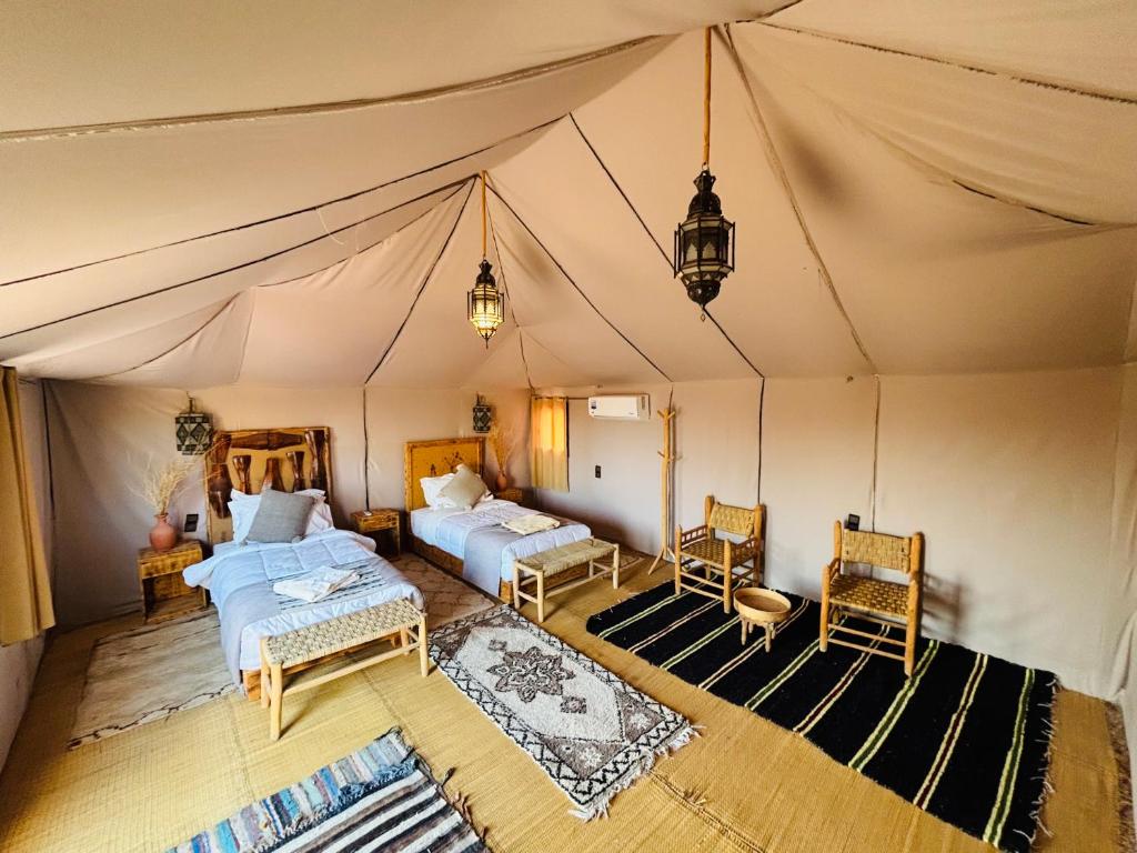 a bedroom with two beds in a tent at Amskou Luxury Desert Camp in Merzouga
