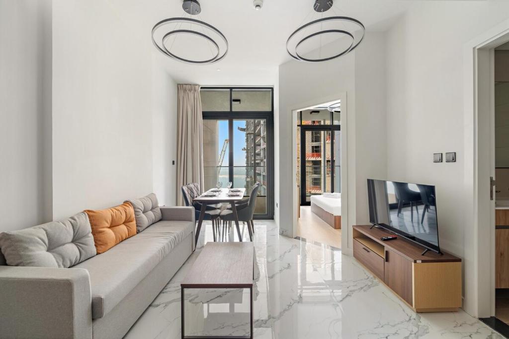 a living room with a couch and a television at FIRST CLASS 1BR Waterfront Bliss in Abu Dhabi