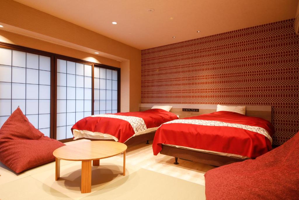 Un dormitorio con dos camas y una mesa y un sofá. en 城崎温泉お宿白山花まんだら, en Toyooka