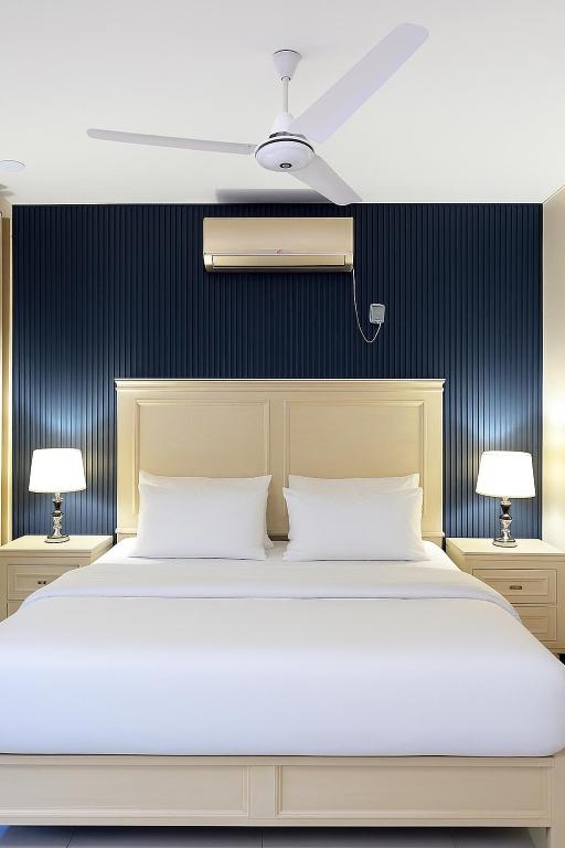 a bedroom with a white bed and two lamps at Nvista Luxe Living in Islamabad