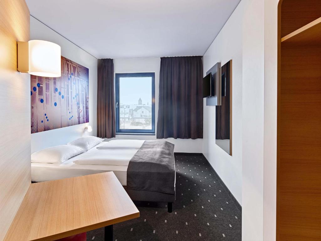 a hotel room with two beds and a table at B&B Hotel Köln-Troisdorf in Troisdorf