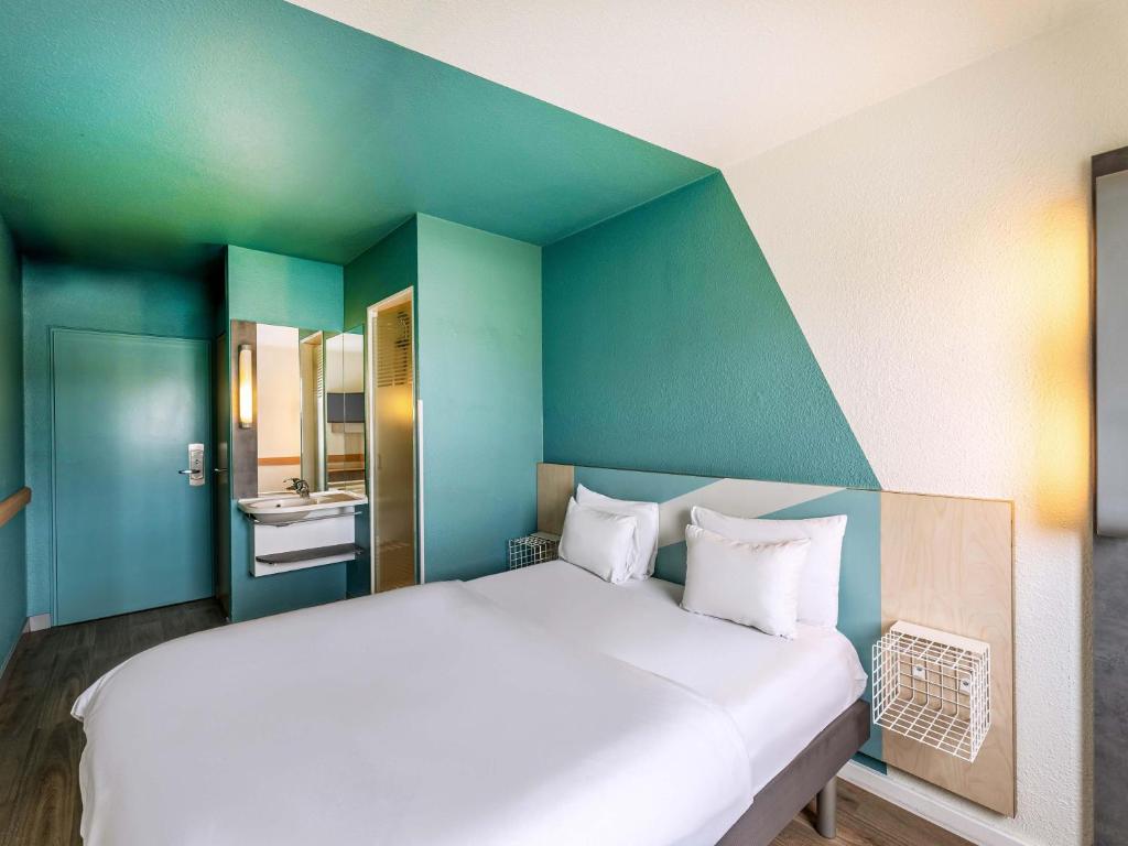a large white bed in a room with green walls at B&B HOTEL Köln-Porz in Cologne