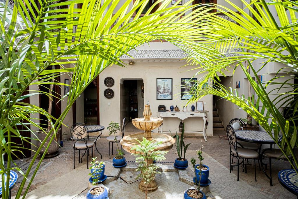 un patio con una fuente, sillas y plantas en Riad Chams Marrakech, en Marrakech