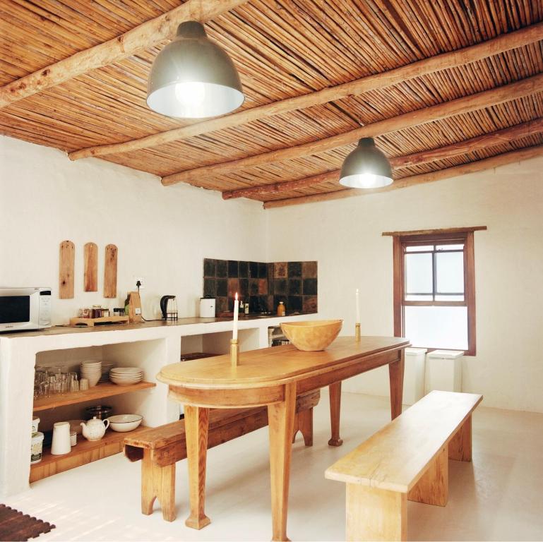 a kitchen with a wooden table and benches in a room at Watsonia Cottage at Waboom Family Farm in Stanford