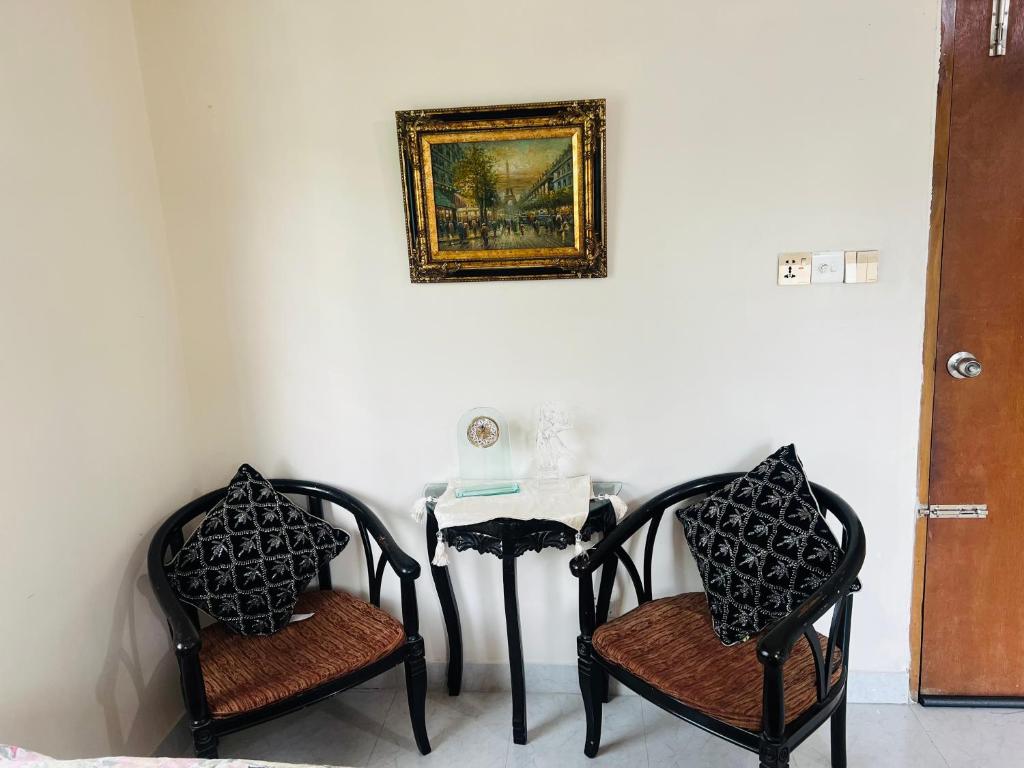 a table with two chairs and a picture on the wall at Gulshan Guest House in Dhaka