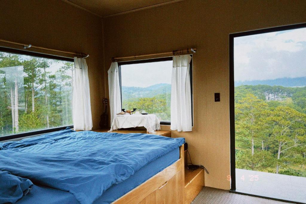 a bedroom with a bed and a large window at Sú Mỏ Choi Đà Lạt in Ðơng Tiêng Liêng