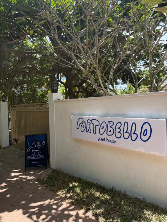 un letrero para una casa de jardín en una pared en Portobello Guest House, en Mirissa