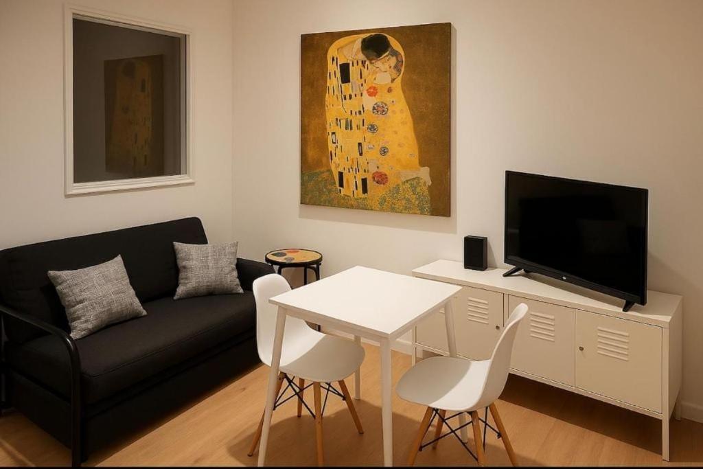 un soggiorno con un divano, un tavolo e una TV di Studio Entièrement Rénové Rue Grande Haute, Sète a Sète
