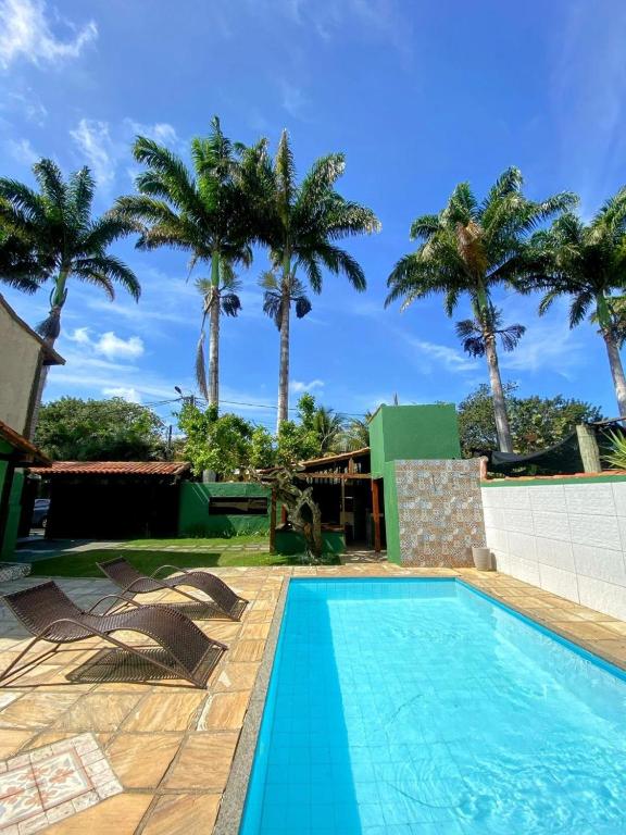 a swimming pool with palm trees in the background at Pousada Villa das Palmeiras in Búzios