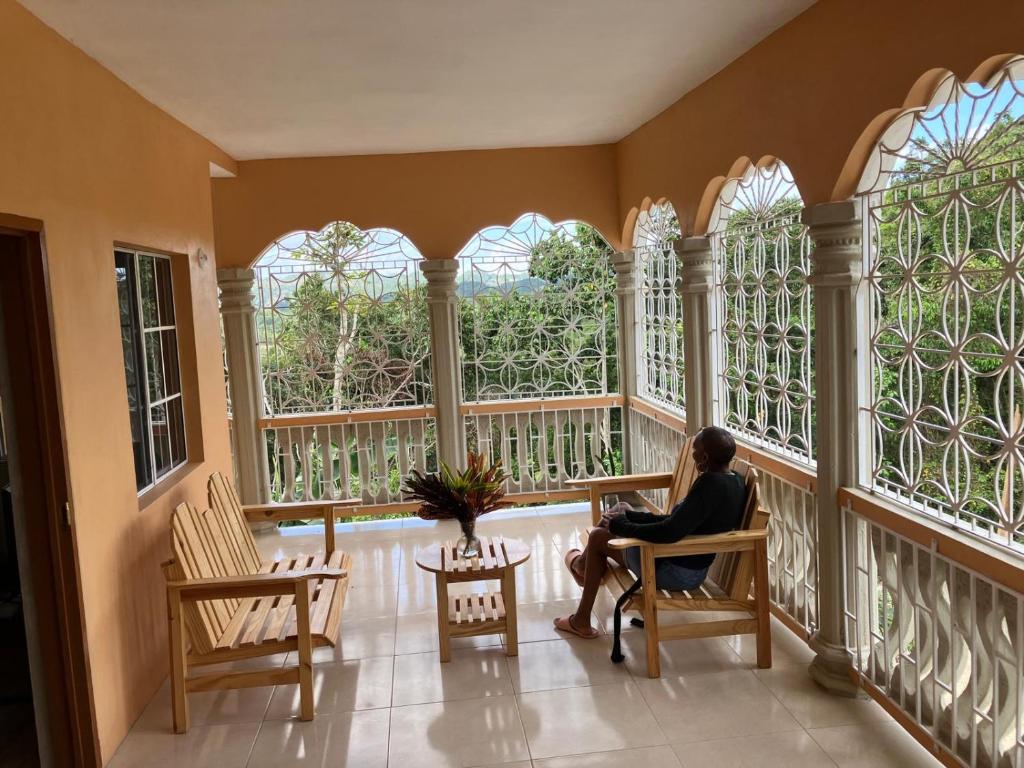 a woman sitting in a chair in a room with windows at A Caribbean Oasis in Stirling