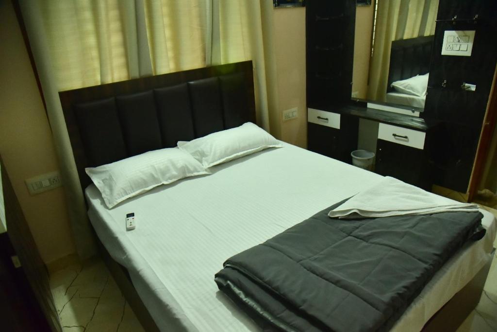a bedroom with a bed with a black headboard and a mirror at Mysuru Family Home Stay in Mysore