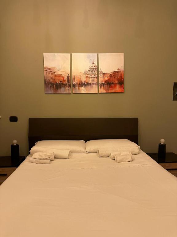 a bed in a room with three paintings on the wall at La Dimora dei Consoli - Apartment San Peter in Rome